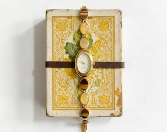 Goldfarbene Schmuckuhr mit gelbem Cabochon.