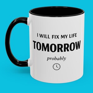 Peut inclure: Mug en céramique blanche avec une anse et un intérieur noirs. Le mug porte l'inscription "I WILL FIX MY LIFE TOMORROW probably" en noir, avec un petit graphique d'horloge. Le mug est posé sur un fond bleu.