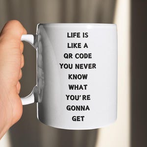 May include: White ceramic mug with black text that reads "Life is like a QR code you never know what you're gonna get".