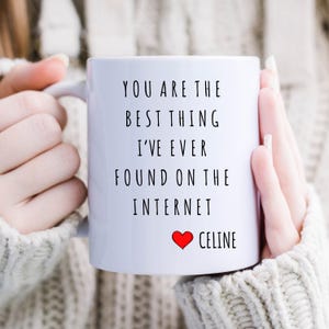 Pode incluir: Caneca de cerâmica branca com texto preto que diz "You are the best thing I've ever found on the internet" com um coração vermelho e o nome "Celine" abaixo.