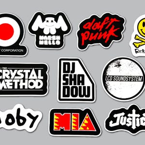 May include: A collection of eleven music-themed vinyl stickers featuring logos and text for artists including Thievery Corporation, Marshmello, Daft Punk, Fatboy Slim, The Crystal Method, DJ Shadow, LCD Soundsystem, Moby, M.I.A., and Justice.