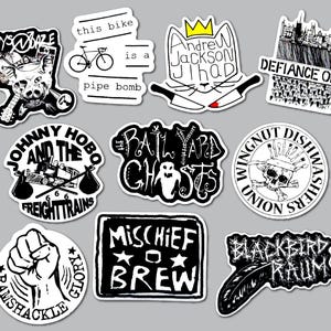 May include: A collection of ten black and white vinyl stickers featuring various band names and graphic illustrations including a pig, a bicycle, a cat with knives, a train, a ghost, a skull, a raised fist, and a feather with text.
