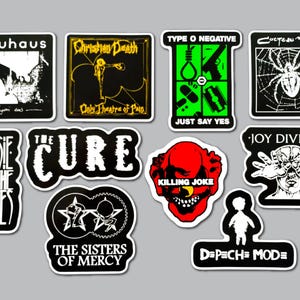 May include: A collection of ten rectangular and die-cut vinyl stickers featuring band logos and album art, including Bauhaus, Christian Death, Type O Negative, Cocteau Twins, Siouxsie and the Banshees, The Cure, Killing Joke, Joy Division, The Sisters of Mercy, and Depeche Mode.