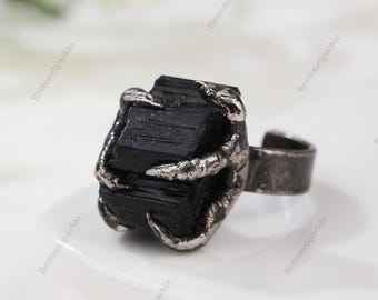 Op de afbeelding: Een ring met een zwarte edelsteen in een klauwvormige zetting. De ring is gemaakt van metaal en heeft een rustieke afwerking.