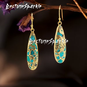 May include: A pair of gold dangle earrings with turquoise blue and gold patterned teardrop-shaped stones.