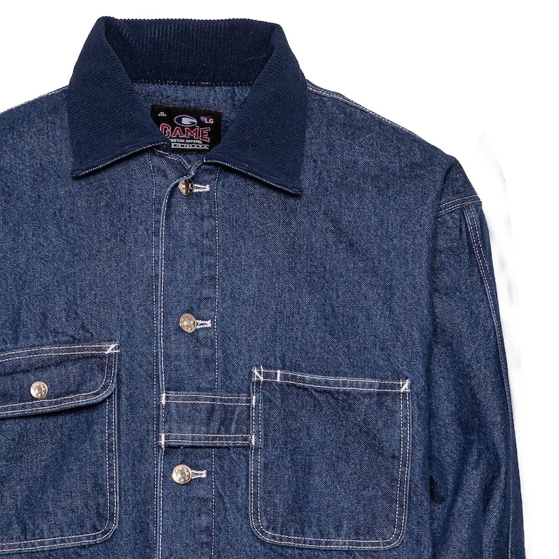 May include: A dark blue denim jacket with a contrasting navy blue corduroy collar. The jacket features two chest pockets and two lower pockets, all with white stitching. The jacket has silver buttons and the brand name "GAME" is visible on a tag.