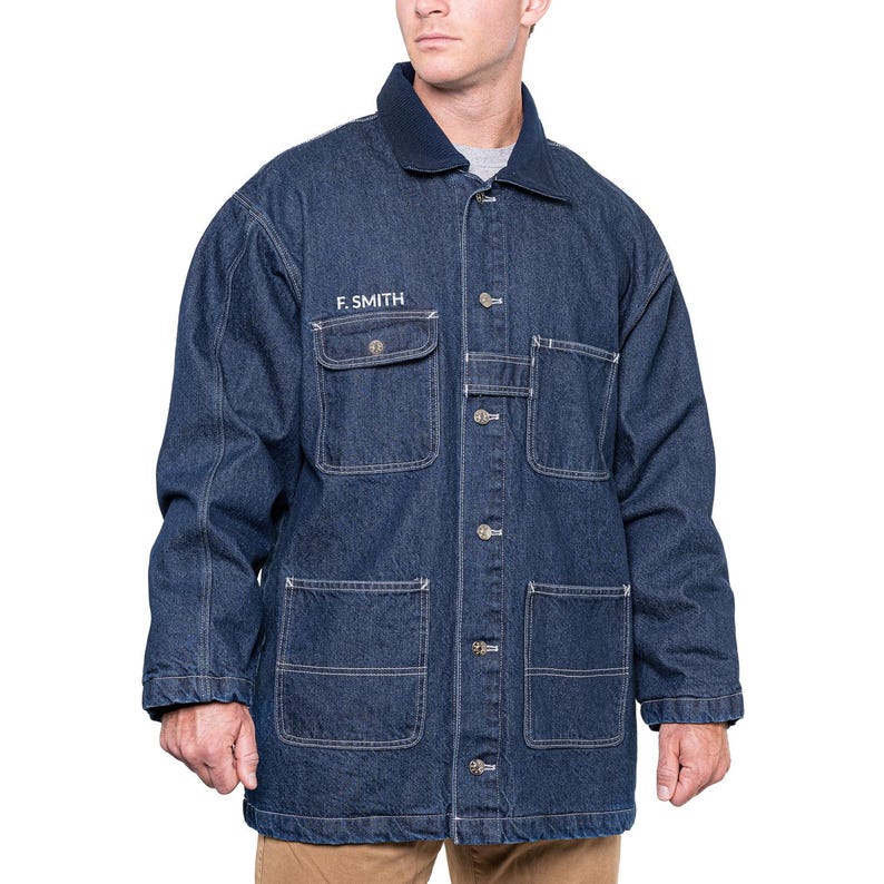 May include: A dark blue denim jacket with a button-up front, four front pockets, and a dark blue collar. The text "F. SMITH" is embroidered on the left chest pocket. The jacket is a workwear style.