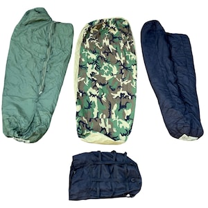 May include: Four sleeping bags in various colors and patterns are displayed against a white background. One is olive green, another is camouflage, and a third is navy blue. A black duffel bag is also present.