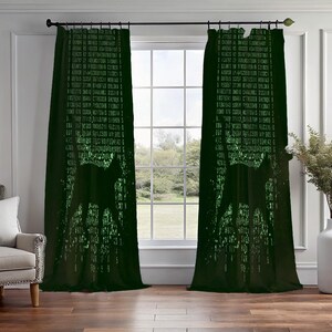 Può includere: Una coppia di tende verde scuro con un motivo ripetuto di caratteri di codice digitale verde chiaro e la sagoma di un gatto al centro. Le tende sono appese a un bastone nero e coprono una finestra con vista su alberi e un cielo nuvoloso.