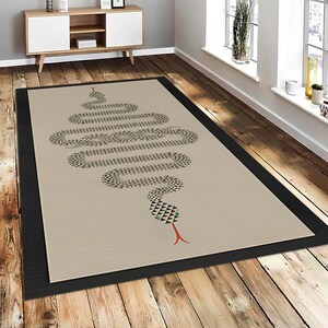May include: A rectangular beige rug with a black border. The rug features a stylized snake design in black and grey, with a red tongue and a turquoise accent. The snake's head is at the top of the rug.