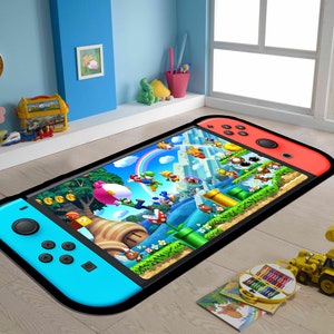 Puede incluir: Una consola Nintendo Switch azul y roja con un borde negro, que se encuentra sobre un suelo de madera. La consola muestra un videojuego con personajes coloridos y un fondo verde.