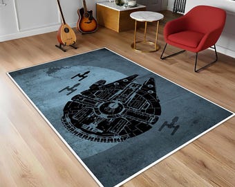 May include: Rectangular area rug featuring a black illustration of the Millennium Falcon spaceship against a blue background. The rug also includes illustrations of other starships. The rug is bordered with a white edge.