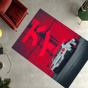 Könnte beinhalten: Rechteckiger Teppich mit einem Design eines weißen und roten Sportwagens auf rotem Hintergrund mit japanischem Text. Der Teppich hat einen dunkelgrauen Rand und liegt auf einer hellgrauen Oberfläche. Das Auto hat rote Rücklichter.