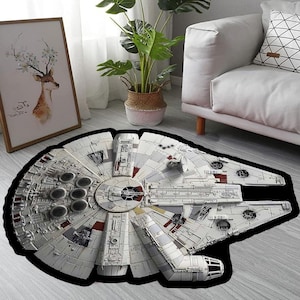 May include: A round, black and white area rug featuring a detailed image of the Millennium Falcon spaceship from Star Wars. The rug is on a light grey floor.