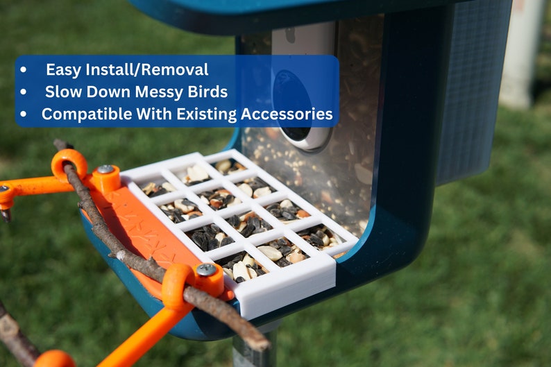 Pu&ograve; includere: Un mangiatoia per uccelli blu con un vassoio bianco a griglia pieno di semi per uccelli. La mangiatoia ha un coperchio in plastica trasparente e un posatoio arancione con un ramo. Il testo "Easy Install/Removal", "Slow Down Messy Birds", e "Compatible With Existing Accessories" &egrave; visibile sulla mangiatoia.