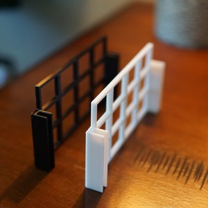 Pu&ograve; includere: Due pannelli a griglia, uno nero e uno bianco, sono mostrati su una superficie di legno. I pannelli sono in plastica e hanno un motivo a griglia.