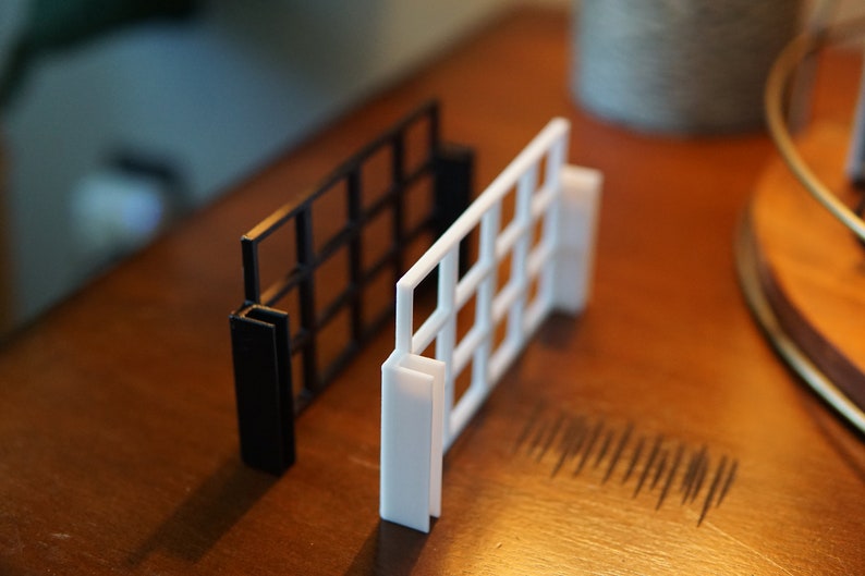 Pu&ograve; includere: Due pannelli a griglia, uno nero e uno bianco, sono mostrati su una superficie di legno. I pannelli sono in plastica e hanno un motivo a griglia.