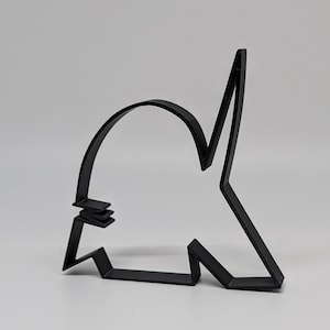 May include: A black metal cookie cutter in the shape of a shark. The cutter has a curved top, a pointed fin, and a jagged bottom edge. The shark cookie cutter is on a white background.