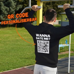 Könnte beinhalten: Schwarzer Hoodie mit dem Text "Wanna Date Me?" und einem QR-Code auf der Rückseite. Der Text "QR Code Personalisierbar" ist in der oberen linken Ecke des Bildes sichtbar.