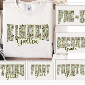 Könnte beinhalten: Cremefarbenes Sweatshirt mit dem Wort "Kindergarten" in einem Tarnmuster. Zusätzliche Karten zeigen "Pre-K", "Second Grade", "Third Grade", "First Grade" und "Fourth Grade" im gleichen Stil.