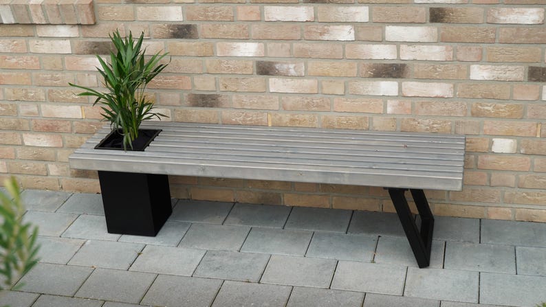 May include: A gray wooden bench with black metal legs and a built-in planter. The planter is filled with a green plant.