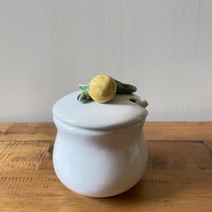 May include: White ceramic sugar bowl with a lid. The lid has a small yellow and green lemon design.