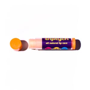 May include: A cylindrical lip balm tube with an orange cap and a dark purple label. The label features the text triptych and all natural lip care in yellow and white, along with three small circular icons depicting animal silhouettes.