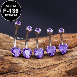 Peut inclure: Cinq anneaux de nombril en titane avec des pierres en forme de cœur violettes. Les anneaux mesurent 8 mm, 10 mm, 12 mm, 14 mm et 16 mm de long. Les anneaux sont en titane ASTM F-136.