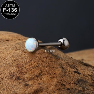 Puede incluir: Un piercing de barra de opalo blanco con una longitud de barra de 5 mm y un calibre de 14. La barra está hecha de titanio y está certificada por ASTM F-136.