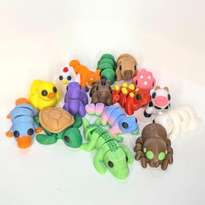 May include: A collection of colourful animal figurines, including a turtle, a chicken, a caterpillar, a cow, a lizard, a spider, a crocodile, a pig, a duck, and a chameleon.