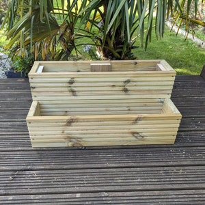 May include: A two-tiered wooden planter box made of natural wood planks. The planter is empty and ready for planting.