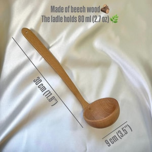 May include: A wooden ladle made of beech wood. The ladle is 30 cm (11.8") long and holds 80 ml (2.7 oz). The ladle's bowl is 9 cm (3.5") wide. The text "Made of beech wood" and "The ladle holds 80 ml (2.7 oz)" are visible.