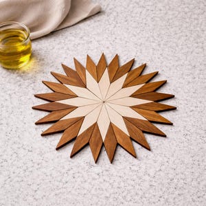 Peut inclure: Un dessous de plat en bois en forme d'étoile. Le dessous de plat est composé d'alternances de pièces de bois claires et foncées, créant un contraste saisissant. Il protège les surfaces des plats chauds et ajoute une touche décorative.