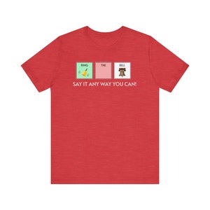 May include: Red t-shirt with a graphic of three squares. The squares say "RING", "THE", and "BELL" with an image of a bell, a ring, and a bell in each square. The text below the squares says "SAY IT ANY WAY YOU CAN!"