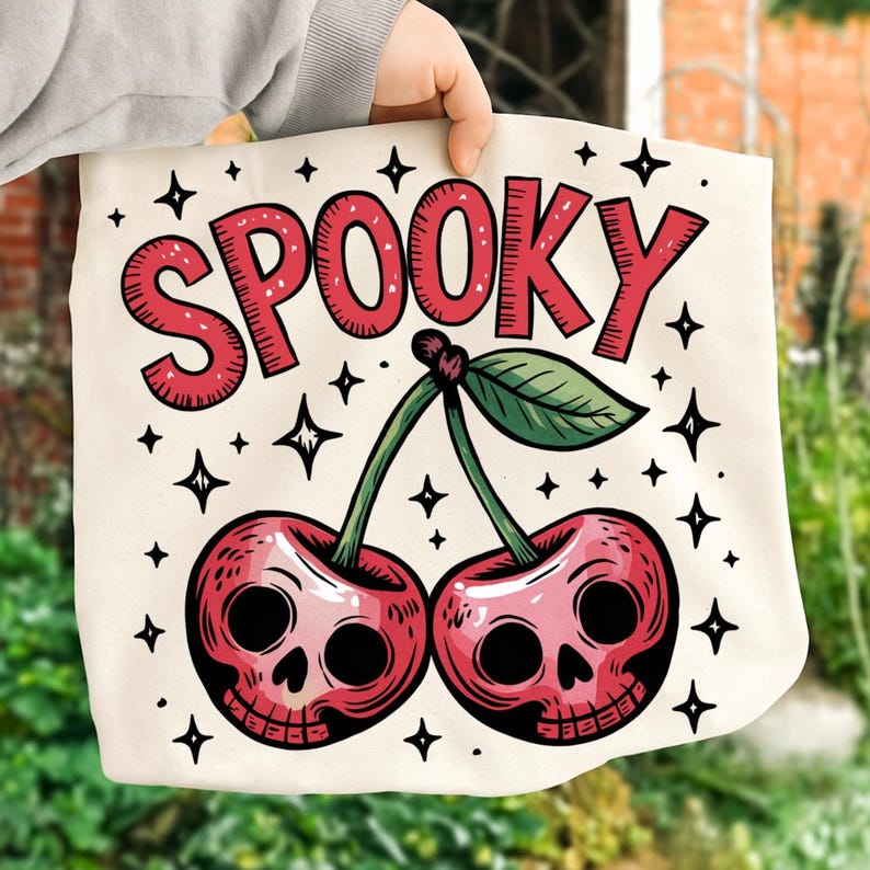 Może przedstawiać: Kremowa torba typu tote z upiornym wzorem. Słowo "SPOOKY" w czerwonych, obrysowanych literach znajduje się nad dwiema wiśniami z twarzami czaszek. Zielone łodygi i liście łączą wiśnie. Czarne gwiazdki otaczają wz&oacute;r.