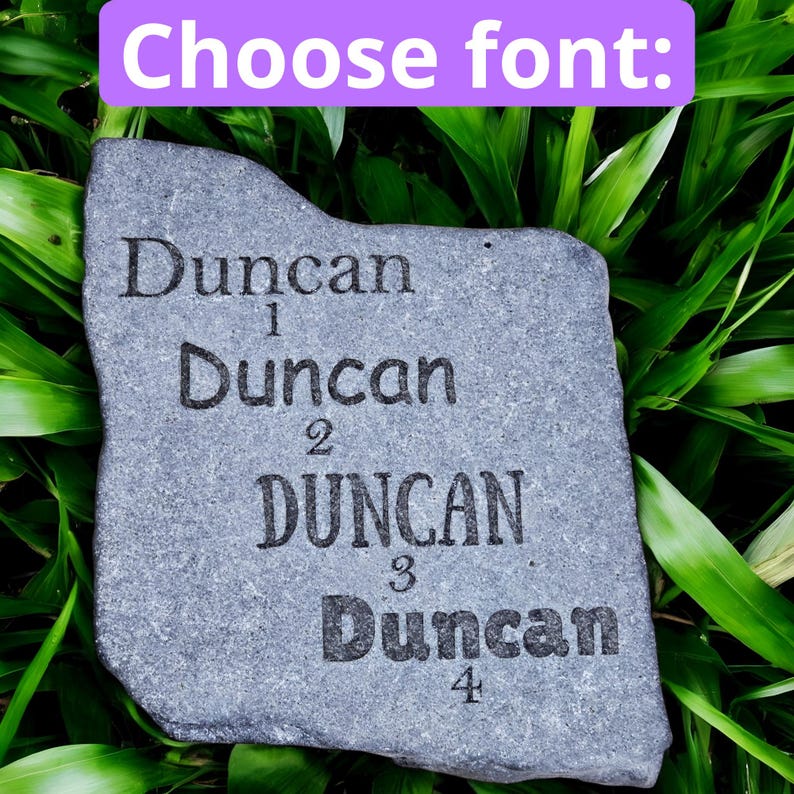 May include: A gray stone plaque with the name "Duncan" engraved four times in different fonts. The text "Choose font:" is in a purple rectangle at the top. The plaque is set against a background of green foliage.