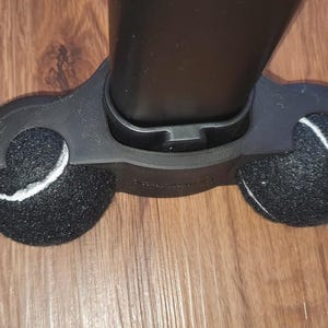 Könnte beinhalten: Schwarzer Staubsaugerkopf mit zwei schwarzen Rädern mit weißen Akzenten. Die Räder bestehen aus einem strukturierten Material. Der Staubsaugerkopf liegt auf einem Holzboden.