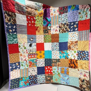 May include: A patchwork quilt constructed from numerous square fabric panels featuring a diverse array of colorful patterns, including roosters, butterflies, horses, geometric shapes, stripes, and various animal prints in red, blue, yellow, and green.