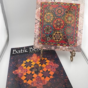 May include: Two softcover quilting books. The top book is titled Serendipity Quilts by Sara Nephew and features a colorful hexagonal quilt pattern. The bottom book is titled Batik Beauty by Laurie J. Shifrin and displays an orange star quilt design.