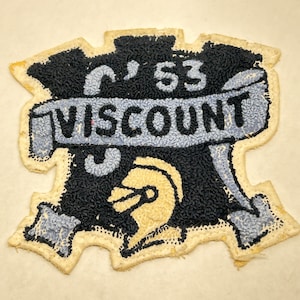 May include: A black and white embroidered patch with a blue banner that reads "'53 VISCOUNT". The patch features a stylized helmet with a white face.