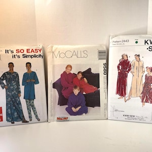 May include: Three sewing pattern envelopes featuring illustrations of loungewear and robes. The left envelope is Simplicity 9541, the center is McCall's 9580, and the right is Kwik-Sew 2443. Each envelope displays garment designs, sizing information, and brand logos.