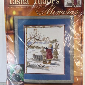 May include: Tasha Tudor's Memories counted cross stitch kit titled Feeding the Birds. The package features a 11 inch by 14 inch finished design of a child in a red coat feeding birds in a snowy landscape. Includes Bucilla branding and text.