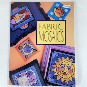 May include: A book titled "Fabric Mosaics" with various colorful mosaic designs. The cover features a yellow and black title box, and several mosaic examples including a fish, a sunflower, and a sun with a face.