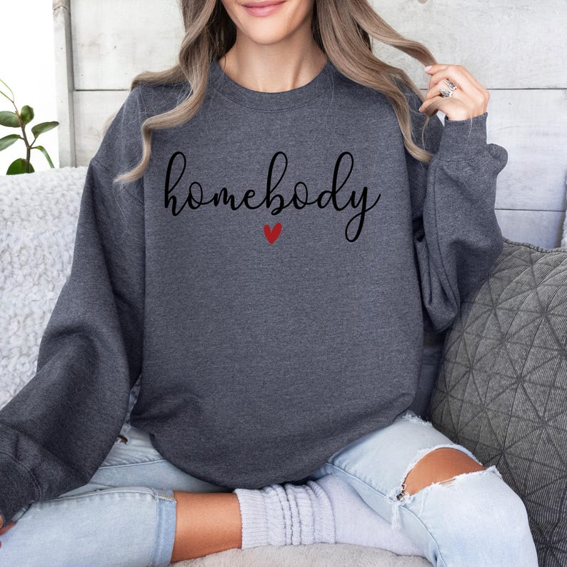 May include: A dark grey sweatshirt with the text "homebody" in black script with a small red heart underneath.