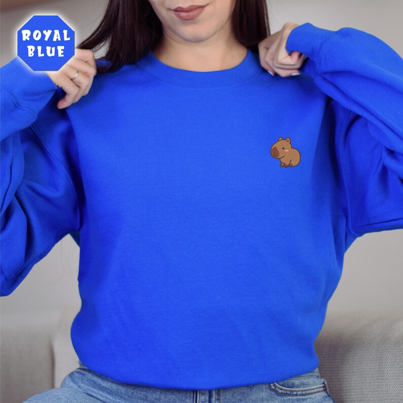 May include: A royal blue sweatshirt with a small embroidered brown capybara on the left chest.