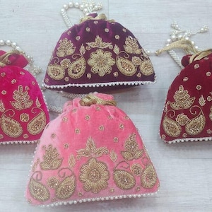 May include: Four velvet drawstring bags with gold embroidery and pearl trim. The bags are in shades of pink, red, and purple.