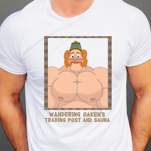 May include: White t-shirt with a cartoon image of a muscular man with a beard and a hat. The text "Wandering Oaken's Trading Post and Sauna" is printed below the image.