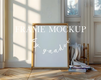 May include: A wooden frame mockup with a white background, sitting on a wooden floor with a blanket and books. The text "FRAME MOCKUP by yaado" is written on the frame.