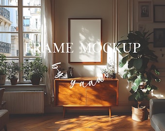 May include: A wooden cabinet with two doors and a light wood finish. The cabinet is in a room with a large window, plants, and a blank picture frame hanging on the wall. The text "FRAME MOCKUP" is written in white on the image.