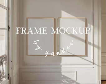 Op de afbeelding: Twee lege fotolijsten met een lichte houten lijst, hangend aan een witte muur met witte lijstwerk. De lijsten hangen naast elkaar en bevinden zich in een kamer met een raam en een deur. De tekst "FRAME MOCKUP" is in witte letters op de muur geschreven.
